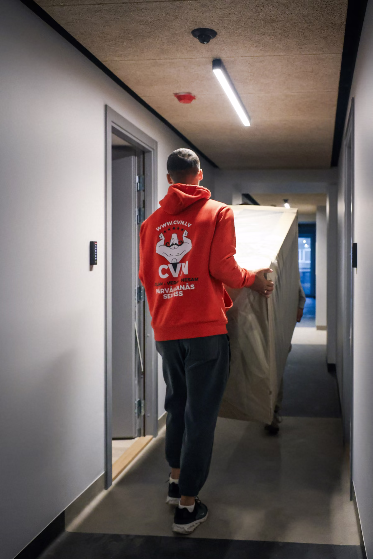 Mover carrying wrapped furniture down a hallway